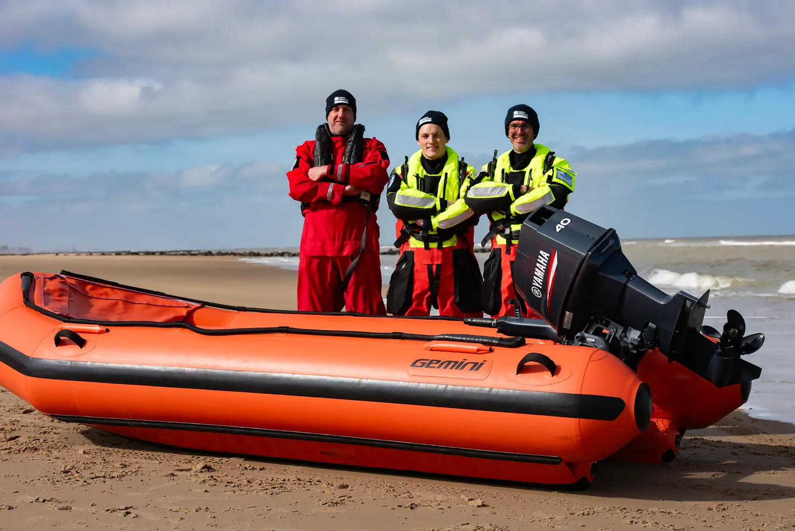 Reddingsteam bij een rode Gemini Marine Swift Water Rescue RIB op het strand