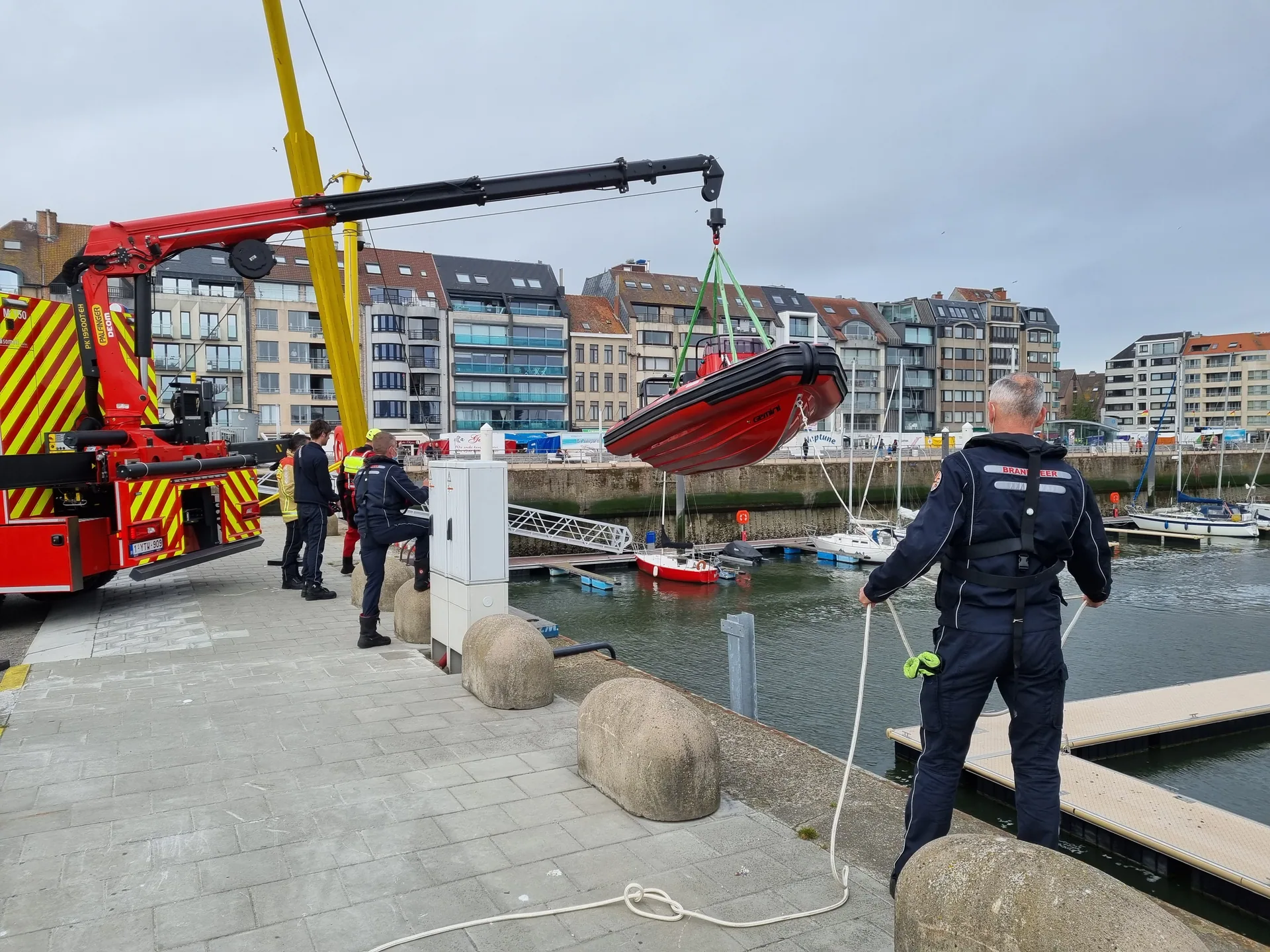 Fire crew launching a red Gemini Marine rescue RIB with a crane